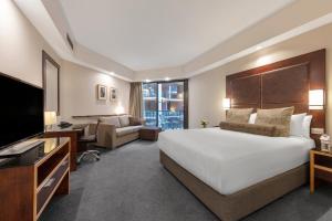 a hotel room with a large bed and a television at Amora Herencia Riverwalk Melbourne in Melbourne +46 photos