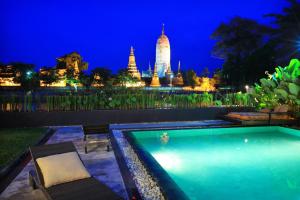 a swimming pool with a view of a temple at night at iuDia Hotel in Phra Nakhon Si Ayutthaya
