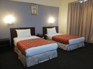 a hotel room with two beds in a room at Hotel Damai in Parit Buntar