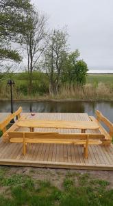 a wooden dock with two benches on a body of water at Sodyba Senoji Rusnė in Rusnė