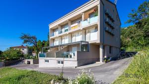 a building on a hill with a blue sky at Rona Studio Apartment Tena in Lovran