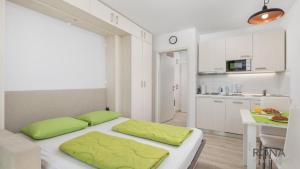 een slaapkamer met een bed met groene kussens erop bij Rona Studio Apartment Tena in Lovran