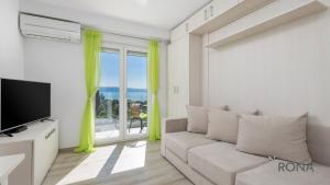 ein Wohnzimmer mit einem Sofa und einem großen Fenster in der Unterkunft Rona Studio Apartment Tena in Lovran