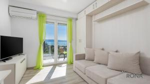 a living room with a couch and a large window at Rona Studio Apartment Tena in Lovran