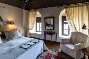 a bedroom with a bed and a chair and windows at Imaret in Kavala