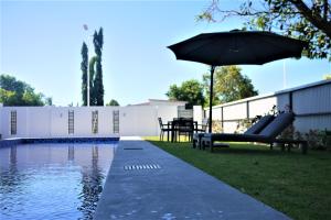 uma piscina com um guarda-sol, uma mesa e cadeiras em Timor Plaza Hotel & Apartments em Dili