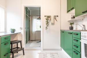 kuchnia z zielonymi szafkami i lustrem w obiekcie Kesäelo w mieście Porvoo