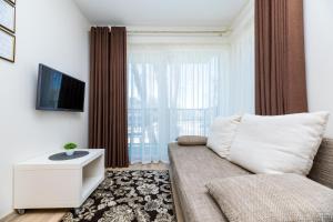 a living room with a couch and a tv at Lunos apartamentai - Centras in Palanga