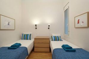 two beds in a white room with blue sheets at Beautiful apartment in Eixample in Barcelona