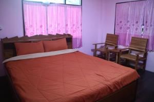 1 dormitorio con 1 cama grande y cortinas rosas en Baanmakpoo บ้านหมากพลู, en Sangkhla Buri