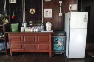 a kitchen with a white refrigerator and a wooden dresser at Baanmakpoo บ้านหมากพลู in Sangkhla Buri