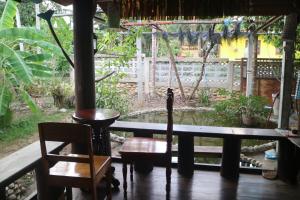 un porche con 2 sillas, una mesa y un estanque en Baanmakpoo บ้านหมากพลู, en Sangkhla Buri