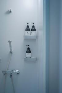 a bathroom with three bottles of soap on shelves at FOLK FOLK Hostel, Cafe & Bar in Ise