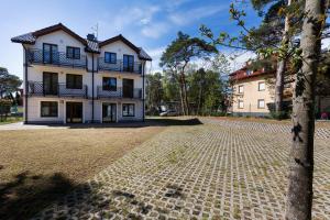 a large white building with balconies on a brick road at Apartamenty Krakowska in Niechorze