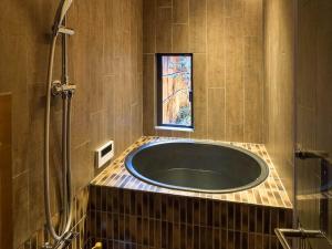 a bathroom with a bath tub with a window at Bonbori an Machiya House in Kyoto
