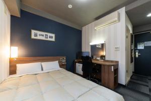 una camera da letto con un letto e una scrivania con un computer di Hotel Econo Tsu Station a Tsu