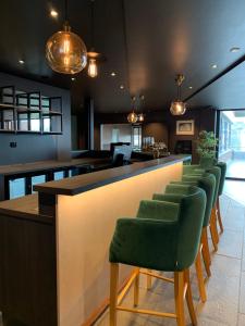 a bar with a row of green bar stools at Hotell Jæren in Bryne