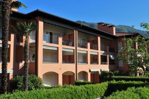 an apartment building with palm trees and bushes at Residenza al Mulin in Ascona