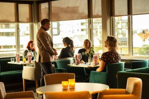 um grupo de pessoas sentadas em mesas em um restaurante em Hotell Jæren em Bryne