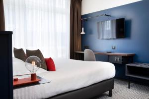 a hotel room with a bed and a tv at Hotel Le Bugatti in Molsheim