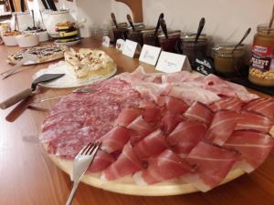 een tafel met een bord vlees op een snijplank bij Room & Breakfast Cà mea Dina in Ledro
