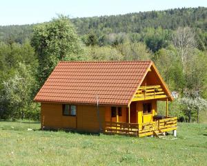 a small house with an orange roof in a field at Przystanek Bieszczady in Stańkowa