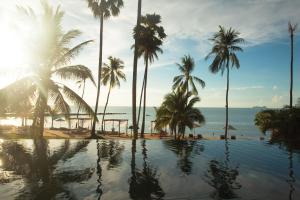 een zwembad aan het strand met palmbomen en de oceaan bij Napasai, A Belmond Hotel, Koh Samui in Mae Nam