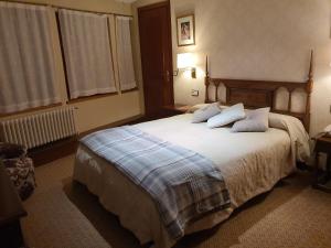 um quarto com uma cama grande com lençóis brancos e almofadas em Fonda Ca la Manyana em Sant Juliá de Vilatorta