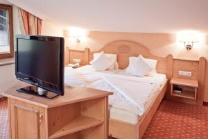 a bedroom with a bed with a flat screen tv at Suitehotel Kleinwalsertal in Hirschegg