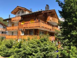 un grande edificio in legno con balconi e alberi di Cornelia a Saas-Fee