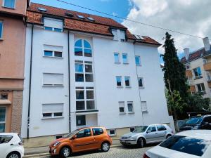 un coche naranja estacionado frente a un edificio blanco en Exklusiv möblierte Wohnung in besten Lage, en Stuttgart