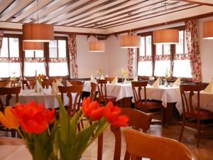 a dining room with tables and chairs and flowers at Gasthaus Engel in Bühlertal
