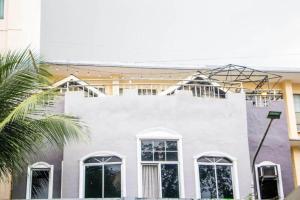 a white building with white windows and a palm tree at Bunks Hostel in Cebu City