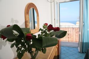 un jarrón de rosas rojas delante de un espejo en Affittacamere Via Muraglione, en Ventotene