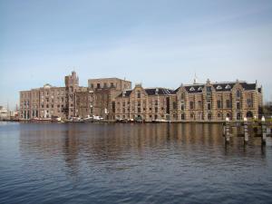 Apartments Zaanse Schans and Amsterdam في Wormer: مبنى كبير جالس على سطح ماء