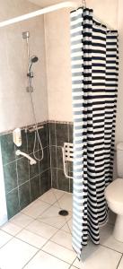 a bathroom with a shower with a black and white curtain at Hotel La Bosselle in Saint-Philbert-de-Grand-Lieu