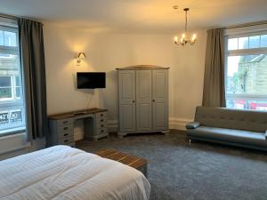 a bedroom with a bed and a tv and a couch at Churchill's Hotel in Wombwell