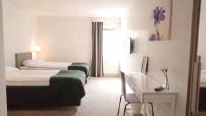 Una habitación de hotel con dos camas y un escritorio. en Övik Eventhotell, en Örnsköldsvik