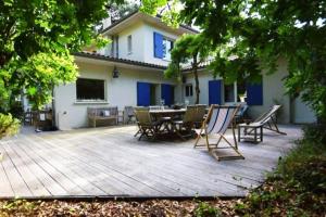 a deck with chairs and a table in front of a house at Charmante villa au Cap Ferret à 2 pas du Bassin in Lège-Cap-Ferret