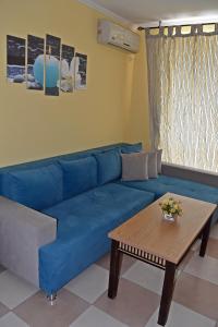 Sofá azul en la sala de estar con mesa en Anvers Apartments, en Sozopol