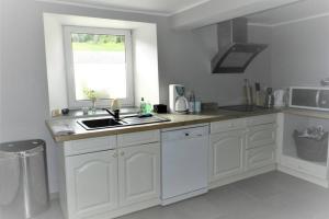 a white kitchen with a sink and a window at Chez Marcel in Fauvillers