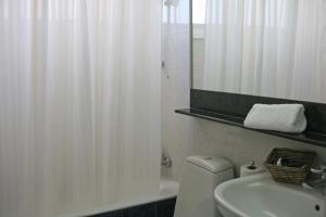 a bathroom with a white shower curtain and a sink at Chrielka Hotel in Limassol