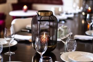 a candle in a jar on a table with wine glasses at Octant Lousa in Lousã