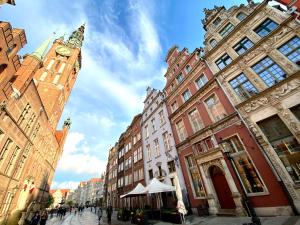 een stadsstraat met gebouwen en een klokkentoren bij Pola by Q4Apartments - heart of the Old Town in Gdańsk