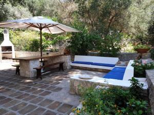 un patio con mesa, sombrilla y bancos en L'Antico Ulivo, en Santa Cesarea Terme