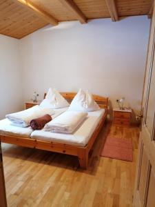 a bedroom with a bed with white sheets and wooden floors at Apartments Scherer in Obertilliach