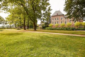 een groot gebouw in een park met bomen en gras bij Het Knechthuys in Baarlo