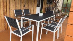 une table à manger et des chaises noires sur une terrasse dans l'établissement Sauna House in North of Lithuania, à Kairiškiai