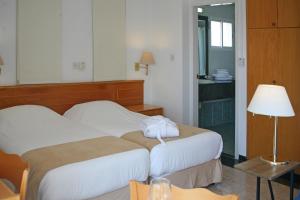 a hotel room with two beds and a lamp at Chrielka Hotel in Limassol
