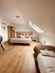a bedroom with two beds and a wooden floor at Atoll Hotel Logis Angers, Beaucouzé in Beaucouzé